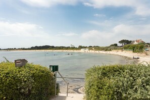 A coastal view with a sandy beach, a clear sky, and a pathway leading to the water. - Villa La Trinité Océan - Accès direct à la plage (La Trinite-sur-Mer)