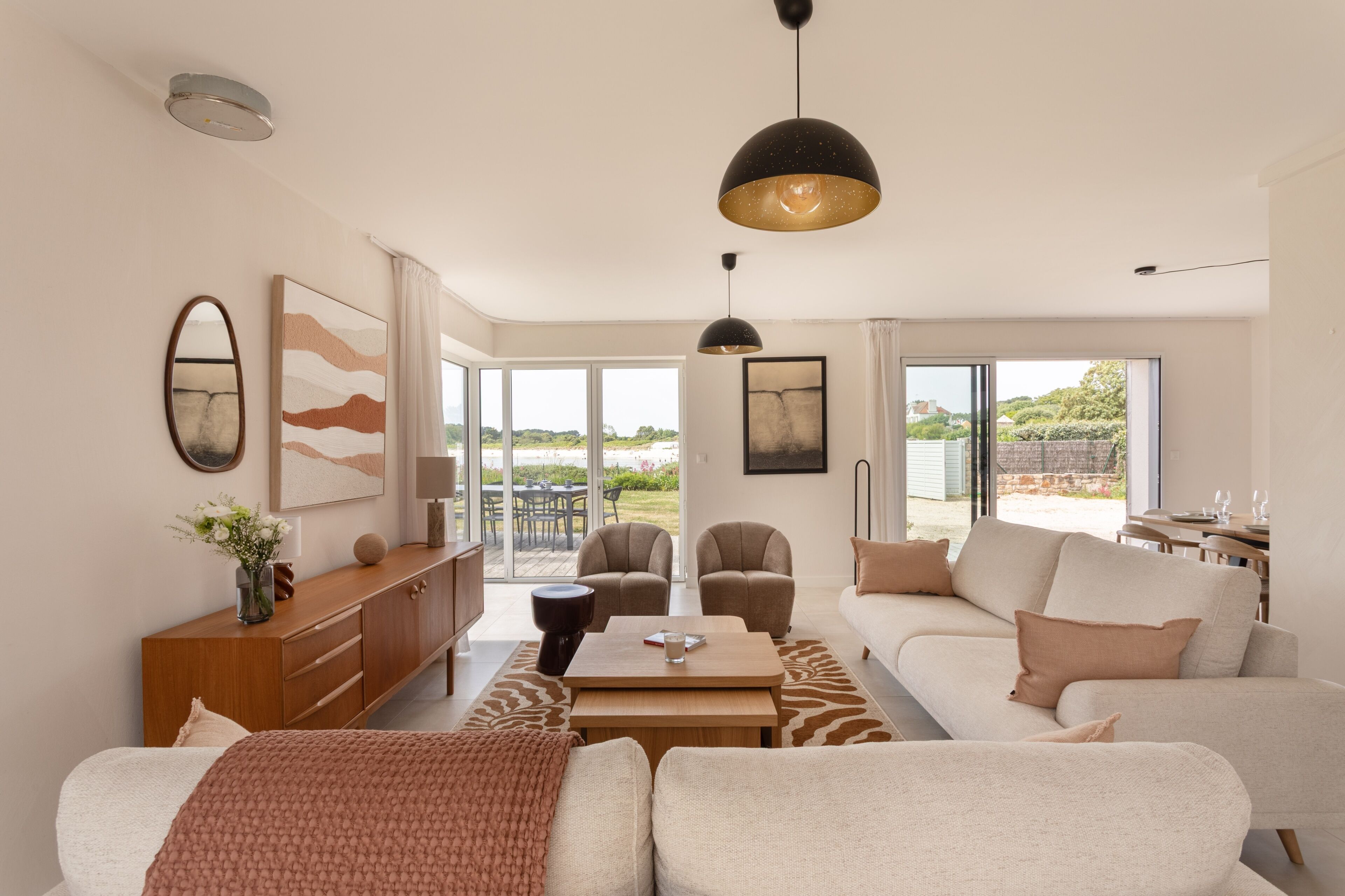 A modern living room with a sofa, coffee table, and chairs, a wooden cabinet, and artwork on the walls.