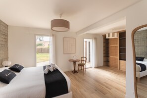 A bedroom with a bed, a chair, a table, a wardrobe, and a view of the outdoors. - Villa La Trinité Océan - Accès direct à la plage (La Trinite-sur-Mer)