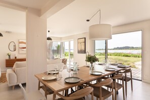 Een eetgedeelte met een grote tafel voor zes personen, uitzicht op de omgeving en een modern interieur.
