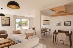 Een moderne woonkamer met een bank, eethoek en uitzicht op de omgeving.