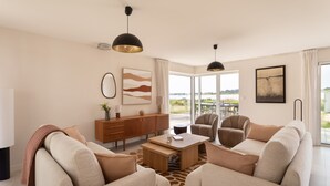 A modern living room with a sofa set, a coffee table, a sideboard, and artwork on the walls. - Villa La Trinité Océan - Accès direct à la plage (La Trinite-sur-Mer)