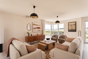 A modern living room with a sofa set, a coffee table, a sideboard, and artwork on the walls. - Villa La Trinité Océan - Accès direct à la plage (La Trinite-sur-Mer)