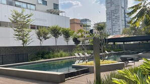A rooftop pool area with lounge chairs, a swimming pool, and a view of surrounding buildings. - #VN1711 | Cyclinn Vila Olímpia (Vila Olímpia)