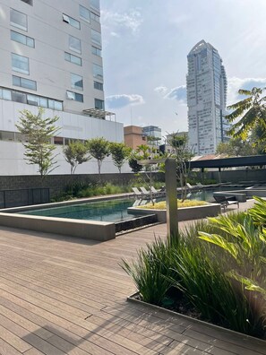 A rooftop pool area with lounge chairs, a swimming pool, and a view of surrounding buildings. - #VN1711 | Cyclinn Vila Olímpia (Vila Olímpia)