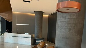 A modern lobby with a reception desk, several seating areas, and large cylindrical columns. - #VN1711 | Cyclinn Vila Olímpia (Vila Olímpia)