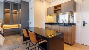 A modern kitchen with a central island, built-in cabinets, and a dining area with chairs. - #VN1711 | Cyclinn Vila Olímpia (Vila Olímpia)