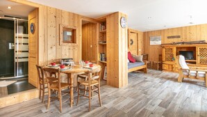 A wooden interior with a dining area, a sofa, a TV, and a bookshelf. - Le Valhalla Chamrousse - Proche Télécabines (Chamrousse)