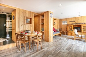 A wooden interior with a dining area, a sofa, a TV, and a bookshelf. - Le Valhalla Chamrousse - Proche Télécabines (Chamrousse)