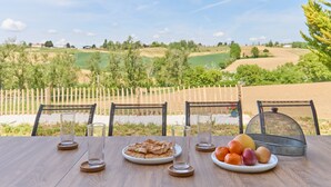 A table set with a plate of bread, a plate of fruit, and two glasses, overlooking a scenic landscape with a wooden fence and trees. - Gîte Le Séquoia de Saint Martin - Maison spacieuse (Seyches)