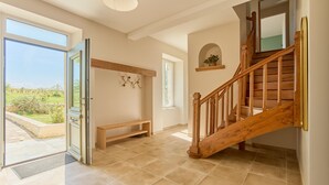 A spacious interior with a wooden staircase, a bench, and a view through a glass door. - Gîte Le Séquoia de Saint Martin - Maison spacieuse (Seyches)