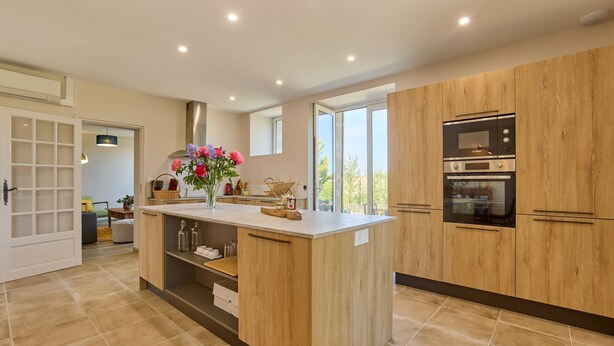 A modern kitchen with wooden cabinetry, a central island, and built-in appliances. - Gîte Le Séquoia de Saint Martin - Maison spacieuse (Seyches)