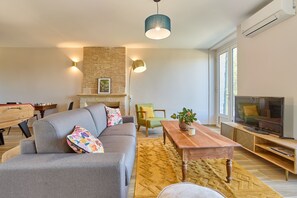 Ein modernes Wohnzimmer mit einer Couch, einem Couchtisch, einem Fernseher und einem Kamin.