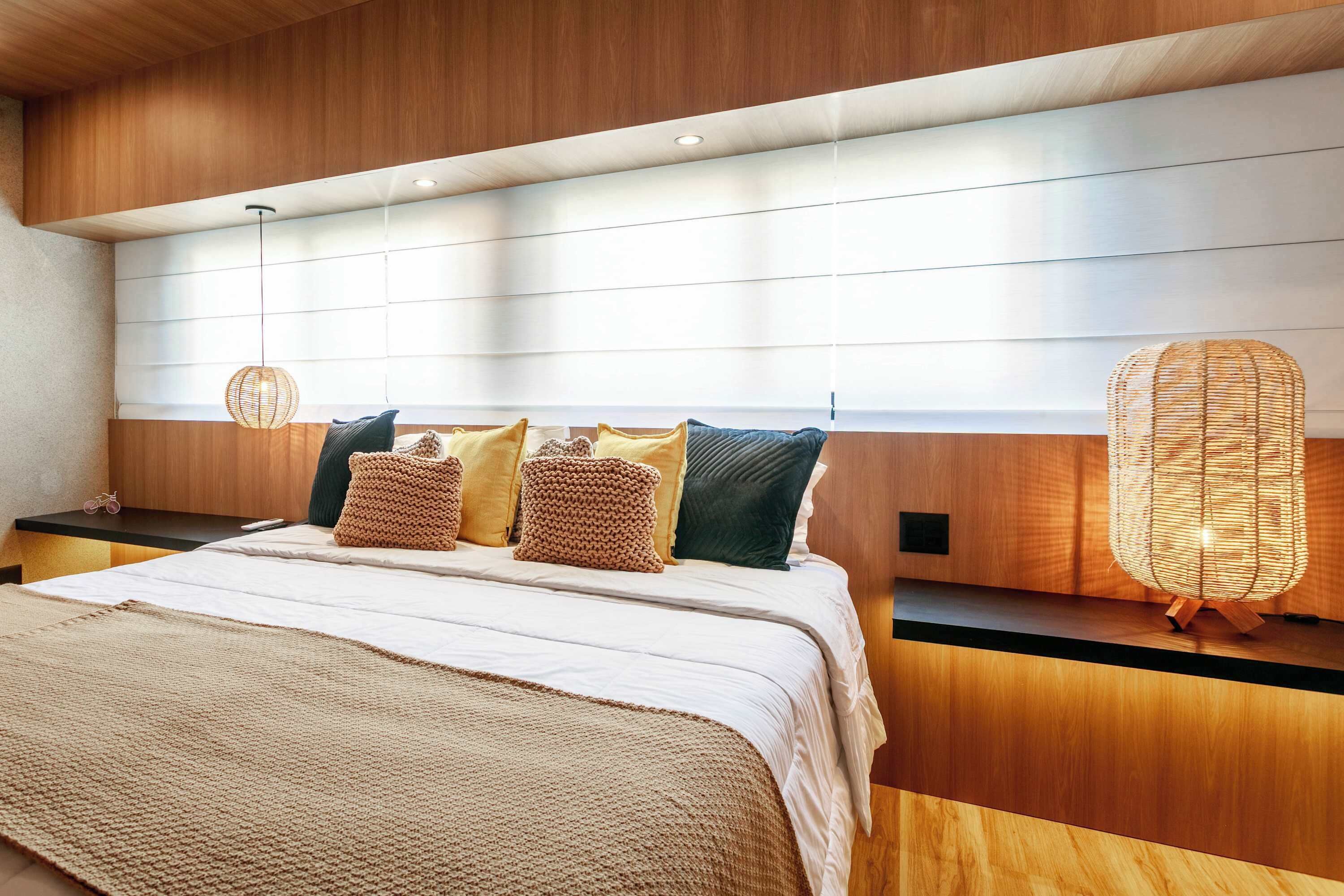 Ein modernes Schlafzimmer mit einem Holzkopfteil, einem großen Bett mit einer beigen Decke und zwei Wandleuchten.