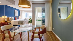 A modern hotel room with a glass dining table, a sofa, a bed, and a balcony with curtains. - #TB413 | Cyclinn Berrini Brooklin (Berrini)