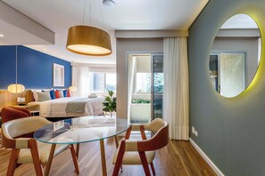 A modern hotel room with a glass dining table, a sofa, a bed, and a balcony with curtains. - #TB413 | Cyclinn Berrini Brooklin (Berrini)