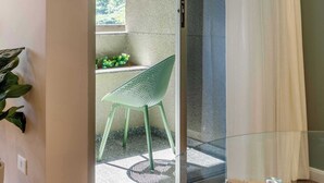 A modern room with a glass door leading to a balcony, a green chair, and a small table. - #TB413 | Cyclinn Berrini Brooklin (Berrini)