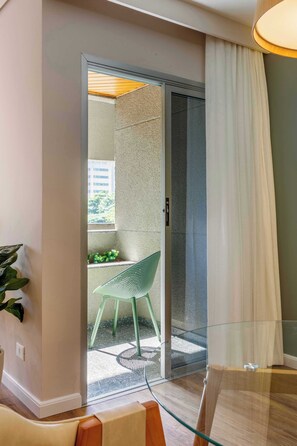 A modern room with a glass door leading to a balcony, a green chair, and a small table. - #TB413 | Cyclinn Berrini Brooklin (Berrini)