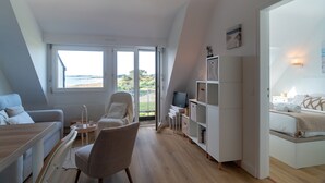 Ett modernt vardagsrum med en soffa, en fåtölj, ett skrivbord och en bokhylla.