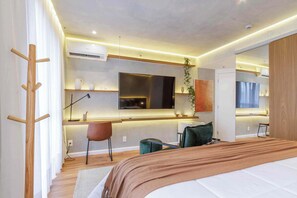 Una habitación de hotel moderna con una cama, un escritorio, una silla y un espejo grande.