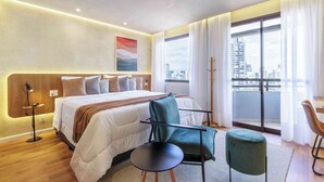 Ein modernes Hotelzimmer mit einem großen Bett, einem Schreibtisch, einem Stuhl und Blick auf die Stadt.