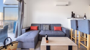 Una sala moderna con un sofá seccional gris, una mesa de centro de madera y un balcón con vistas.