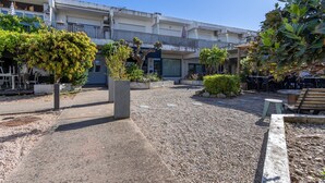 Un patio con sendero de grava, plantas en macetas y mobiliario exterior.