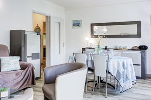 Ein modernes Wohnzimmer mit Sofa, Sessel, Esstisch und Küchenbereich.