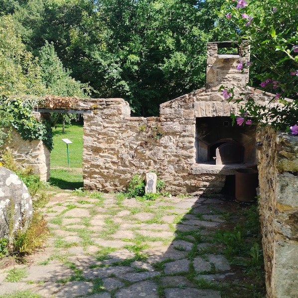 Ein Steinhaus mit Schornstein, einem Kiesweg und einer Rasenfläche.