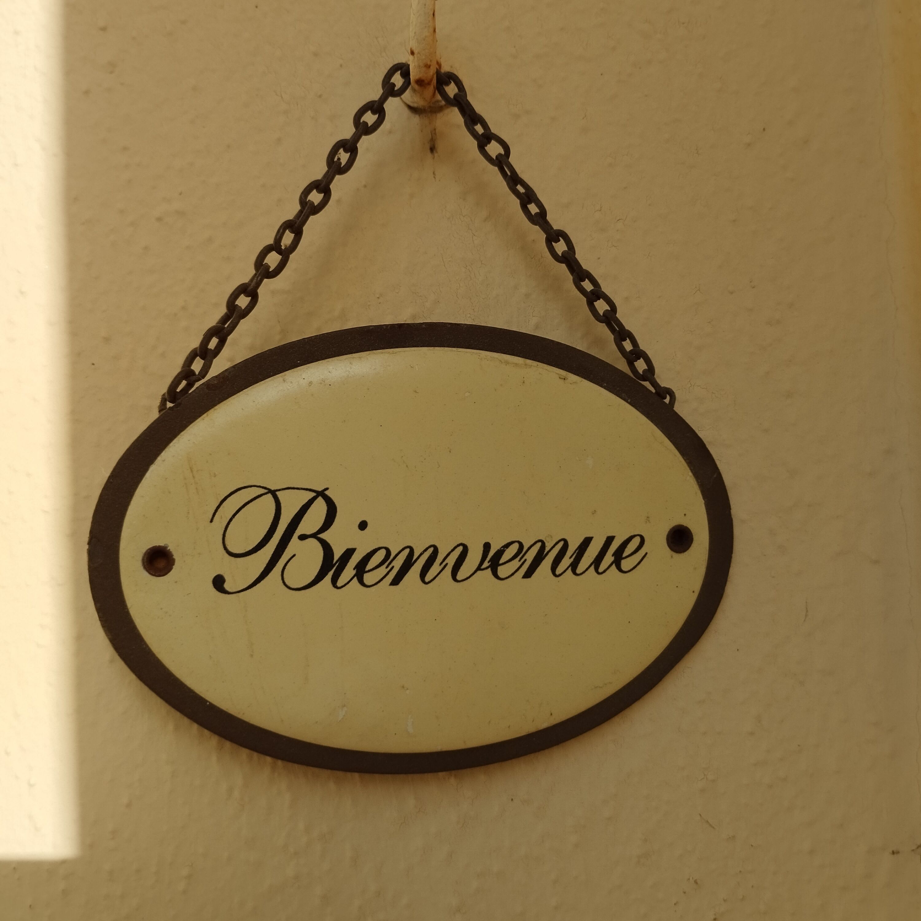 Una señal circular con la palabra 'Bienvenue' en una pared.