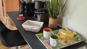 Un bancone cucina con una macchina per il caffè, una pianta, un vassoio con una scatola di cereali English breakfast e due tazze.