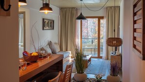 Ein gemütliches Zimmer mit einem Holztisch, einer Couch und einem großen Fenster mit Vorhängen.