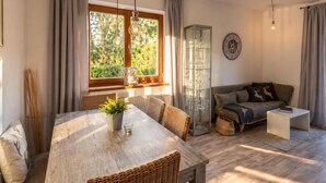 A living room with a dining table, wicker chairs, a sofa, a glass cabinet, and a clock on the wall. - Relaxing break on the sunny slope with garden (Westendorf)