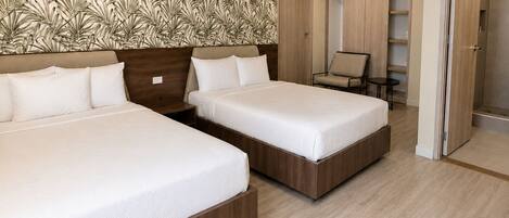 Een hotelkamer met twee bedden, een houten hoofdbord, een behang met patroon, een stoel en een inloopkast.