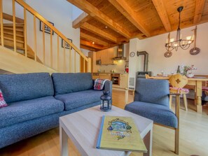 A modern living room with a sofa, armchair, and a table with a book. A staircase is visible in the background. - Lovely chalet with a large garden and terraces (Kötschach-Mauthen)