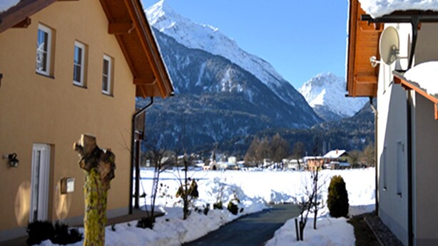 A building with a snow-covered roof, a pathway leading to a mountain, and a clear sky. - Lovely chalet with a large garden and terraces (Kötschach-Mauthen)