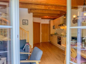 A cozy interior with a wooden ceiling, a kitchen with modern appliances, and a dining area with a table set for two. - Lovely chalet with a large garden and terraces (Kötschach-Mauthen)