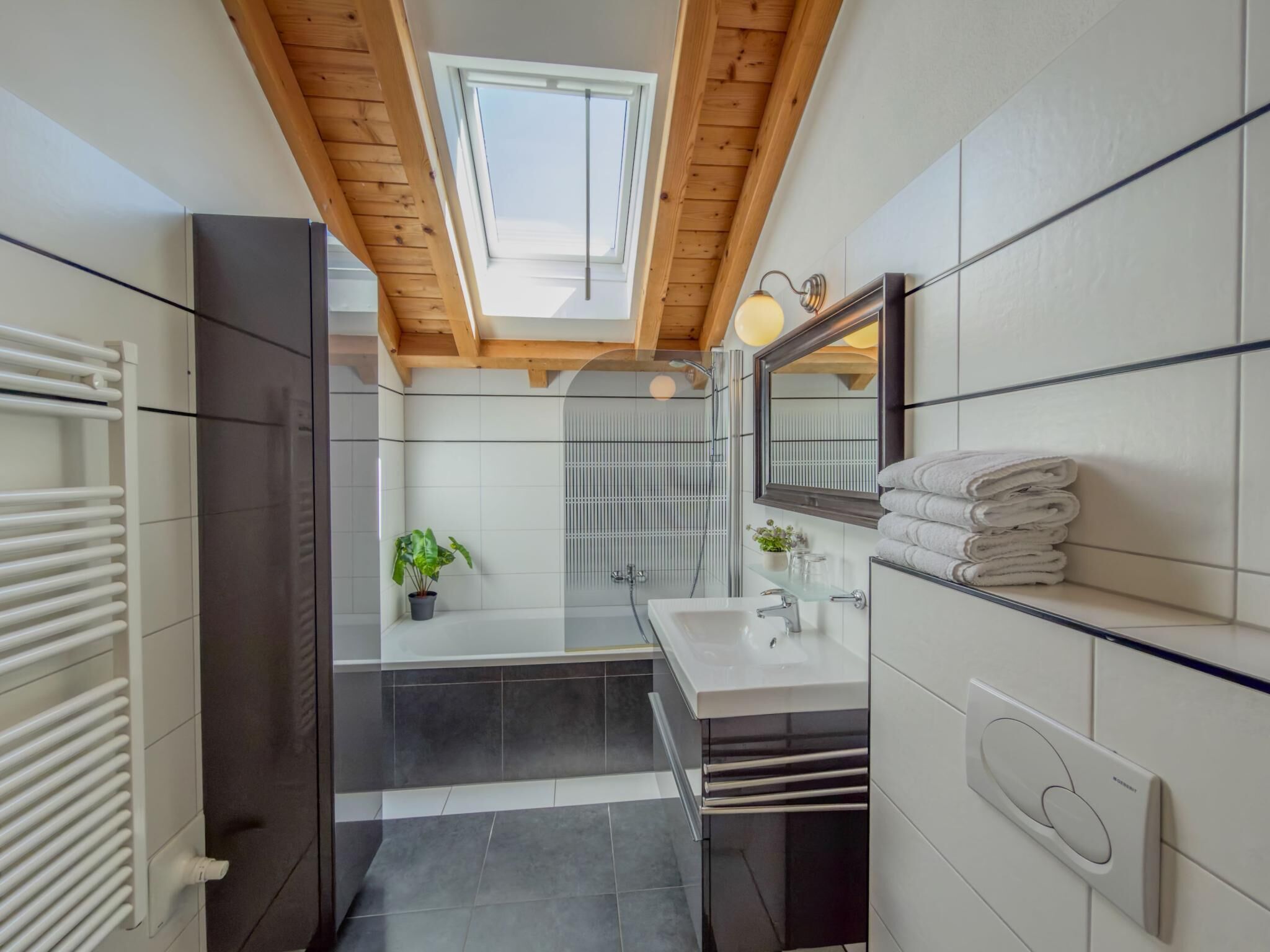 Une salle de bain moderne avec un puits de lumière, une cabine de douche en verre et un sol carrelé de blanc.