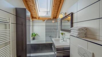 Une salle de bain moderne avec un puits de lumière, une cabine de douche en verre et un sol carrelé de blanc.