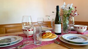 A dining table set with plates, glasses, a bottle of wine, a vase with flowers, and a bowl of pretzels. - Lovely chalet with a large garden and terraces (Kötschach-Mauthen)