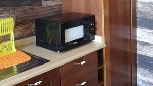 Una cocina con armarios de madera, microondas y tabla de cortar amarilla.