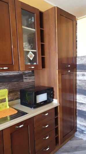 A kitchen with wooden cabinets, a microwave, and a yellow cutting board.