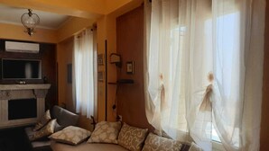 Una habitación con sofá, chimenea, televisión y cortinas de gasa.