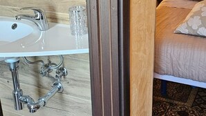 Un baño con un lavamanos blanco, un vaso y un perchero para toallas.