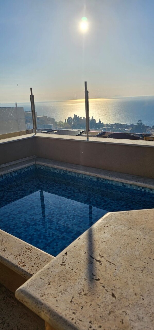 Ein Pool auf dem Dach mit freiem Blick auf das Meer und die Skyline der Stadt.