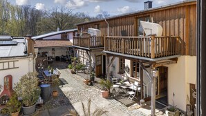 A wooden building with a balcony, outdoor seating, and potted plants.