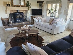 A living room with a fireplace, sofa, TV, and a stone fireplace surround. - Authentic Charente house in a quiet natural area (La Villedieu)