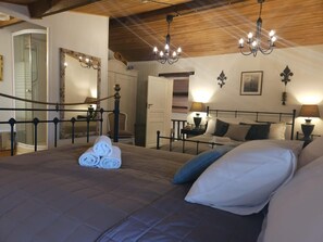 A bedroom with a large bed, a chandelier, and a mirror. - Authentic Charente house in a quiet natural area (La Villedieu)
