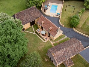 Ein Wohnhaus mit Swimmingpool, überdachter Terrasse und Auffahrt.