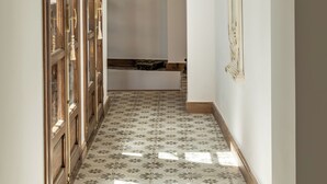 Un couloir avec des poutres en bois, un sol carrelé et un escalier.